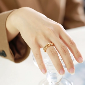 Détail d'une bague gourmette en or poli portée au doigt pour femme élégante
