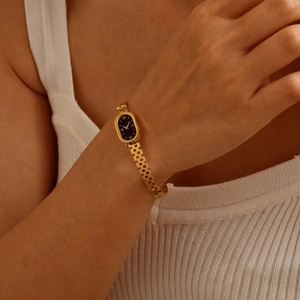 Détail macro d'un bracelet montre vintage doré avec chiffres romains sur cadran noir