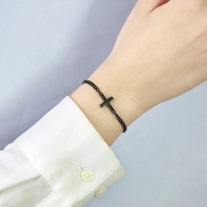Close-up of a minimalist black cross pendant bracelet on a woman wrist for daily wear