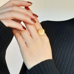 Close-up of a wide 18K gold polished signet ring on a model with red nails