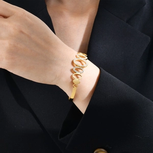 Détail de joncs ovales dorés avec incrustation de zircon portés par un mannequin en tailleur