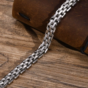 Detail eines silbernen Edelstahl-Panzerarmbands auf Vintage-Leder und Holz Hintergrund