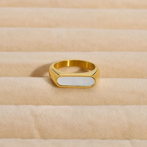 Gros plan détaillé d'une bague géométrique en acier doré avec incrustation blanche