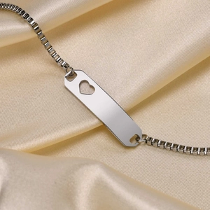 Macro shot of silver stainless steel box chain bracelet with heart cutout ID plate