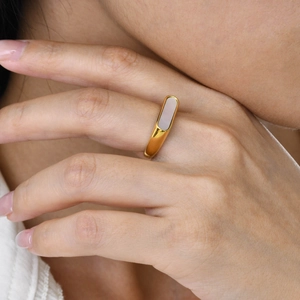 Détail d'une bague géométrique dorée avec incrustation en nacre sur un mannequin
