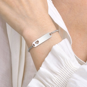 Detail of gold box chain bracelet with heart cutout and customizable ID tag on wrist