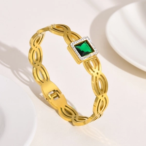Détail du bracelet doré avec pierre verte taille émeraude et accents de zircon blanc