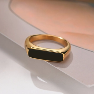 Détail d'une bague chevalière dorée avec insert rectangulaire en émail noir