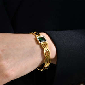 Détail du bracelet doré avec une pierre précieuse verte carrée et des zircons incrustés
