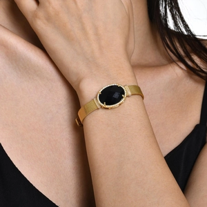 Détail du bracelet à maille dorée avec pierre noire ovale et micro-pave de cristaux brillants