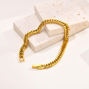 Gros plan détaillé du bracelet gourmette doré sur pierre montrant texture et fermoir