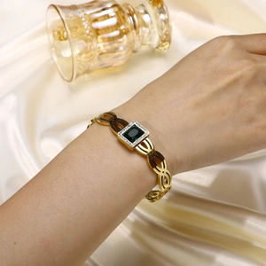 Détail d'un bracelet doré orné d'une pierre verte taille émeraude et de zircons fins