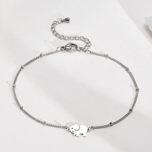 Détail d'un pendentif éléphant poli sur une chevillère minimaliste en acier inoxydable