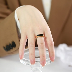 Bague géométrique minimaliste dorée élégante avec incrustation noire sur la main