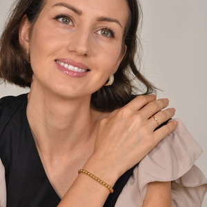 Details eines minimalistischen Goldperlenarmbands und passenden Rings am Modell
