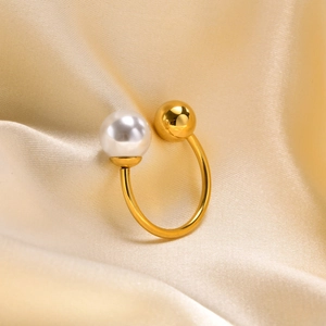 Détail de la boucle d'oreille en U dorée avec perle blanche et boule en métal poli