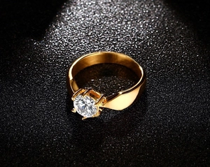 Macro di un anello in acciaio al titanio dorato con zircone solitario a taglio tondo