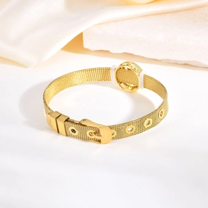 Détail du bracelet en maille d'acier inoxydable doré avec boucle et breloque sur satin
