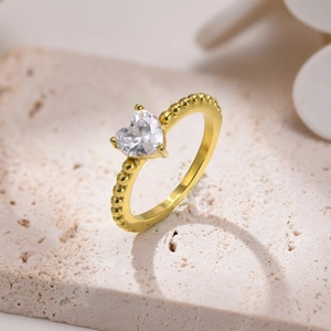 Dettaglio dello zircone a cuore su un anello in acciaio inossidabile dorato con sfere