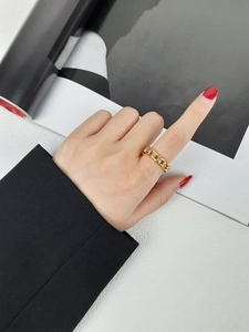 Gros plan d'une bague maillon de chaîne dorée pour femme au style minimaliste moderne