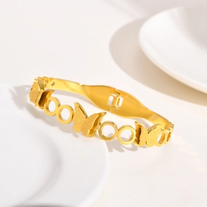 Détail d'un bracelet doré avec motifs papillons ajourés et finition sablée scintillante