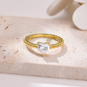 Dettaglio dell'anello cuore in zircone dorato con fascia a sfere su pietra