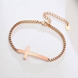 Detail of rose gold box chain bracelet featuring a horizontal cross and lobster clasp