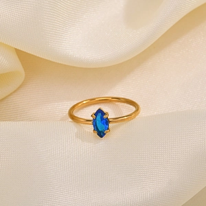 Detail of a thin gold stainless steel ring with a marquise-cut blue zircon on silk