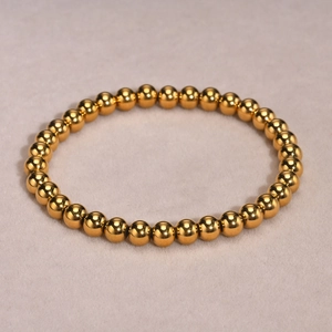 Detailansicht eines polierten goldenen Perlenarmbands mit spiegelndem Metallglanz