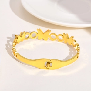 Gros plan des maillons papillon dorés et du fermoir à pression sur le bracelet jonc