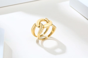 Gros plan d'une bague double chaîne dorée sur un fond blanc géométrique minimaliste