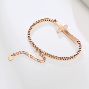 Detail of rose gold stainless steel box chain bracelet featuring a brushed cross element