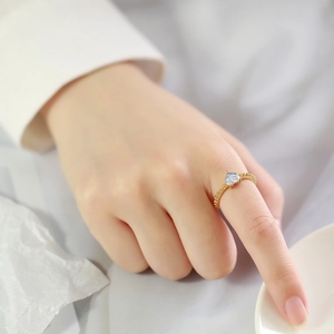 Dettaglio anello con zircone a cuore e fascia dorata con texture a microsfere