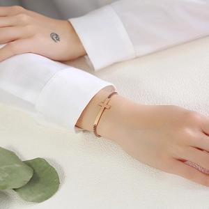 Close-up of rose gold stainless steel cross bracelet with elegant box chain on wrist
