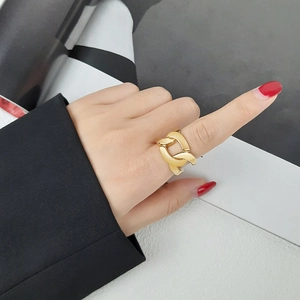 Détail macro d'une bague à maillons dorés portée à l'index avec un style minimaliste élégant