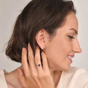 Detail shot of a gold ring with marquise-cut blue zircon and elegant drop chain earrings