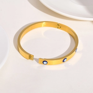 Gros plan du bracelet doré avec porte-bonheur œil bleu et détail du fermoir mécanique