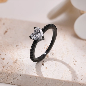 Dettaglio dell'anello con zircone a cuore, fascia nera con perline e montatura a 4 griffe