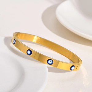 Vue macro détaillée du bracelet doré à charnière orné de symboles protecteurs du mauvais œil