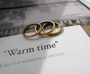Close-up of three-piece 18K gold-plated stainless steel rings with frosted detail on a card