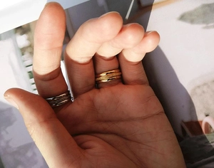 Detail of stacked stainless steel rings with gold and silver finishes and frosted texture