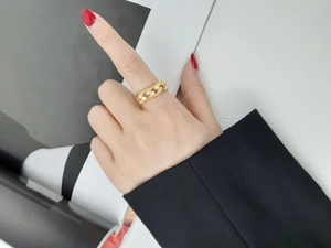 Gros plan d'une bague chaîne à maillons dorés portée avec une tenue de bureau élégante