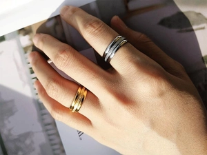 Close-up of gold and silver stacked triple rings with sparkling frosted texture on fingers
