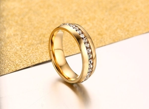Close-up of gold titanium steel ring with inlaid sparkling crystals on shiny background