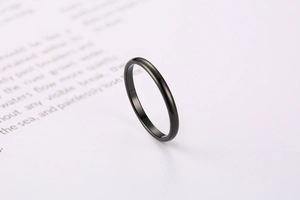 Close-up of minimalist black plated stainless steel thin band ring on magazine