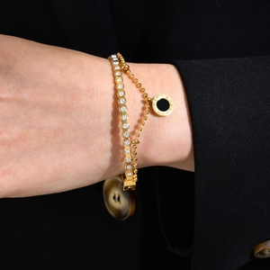 Gros plan d'un bracelet double rang en or avec zircons et pendentif disque noir