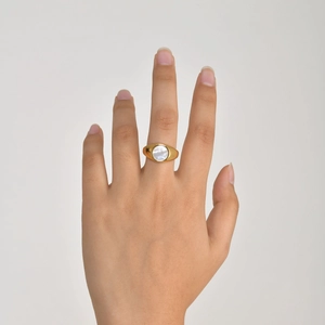 Close-up of golden signet ring featuring an oval white mother of pearl inlay detail
