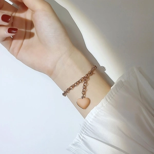 Gros plan d'un bracelet à pendentif cœur en acier inoxydable or rose au poignet