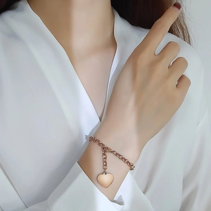 Gros plan d'un bracelet doré rose avec pendentif coeur porté élégamment par un mannequin