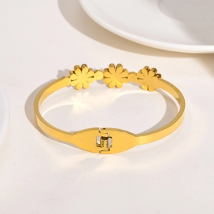 Gros plan d'un bracelet doré en forme de fleur avec fermoir à ressort et détails ciselés